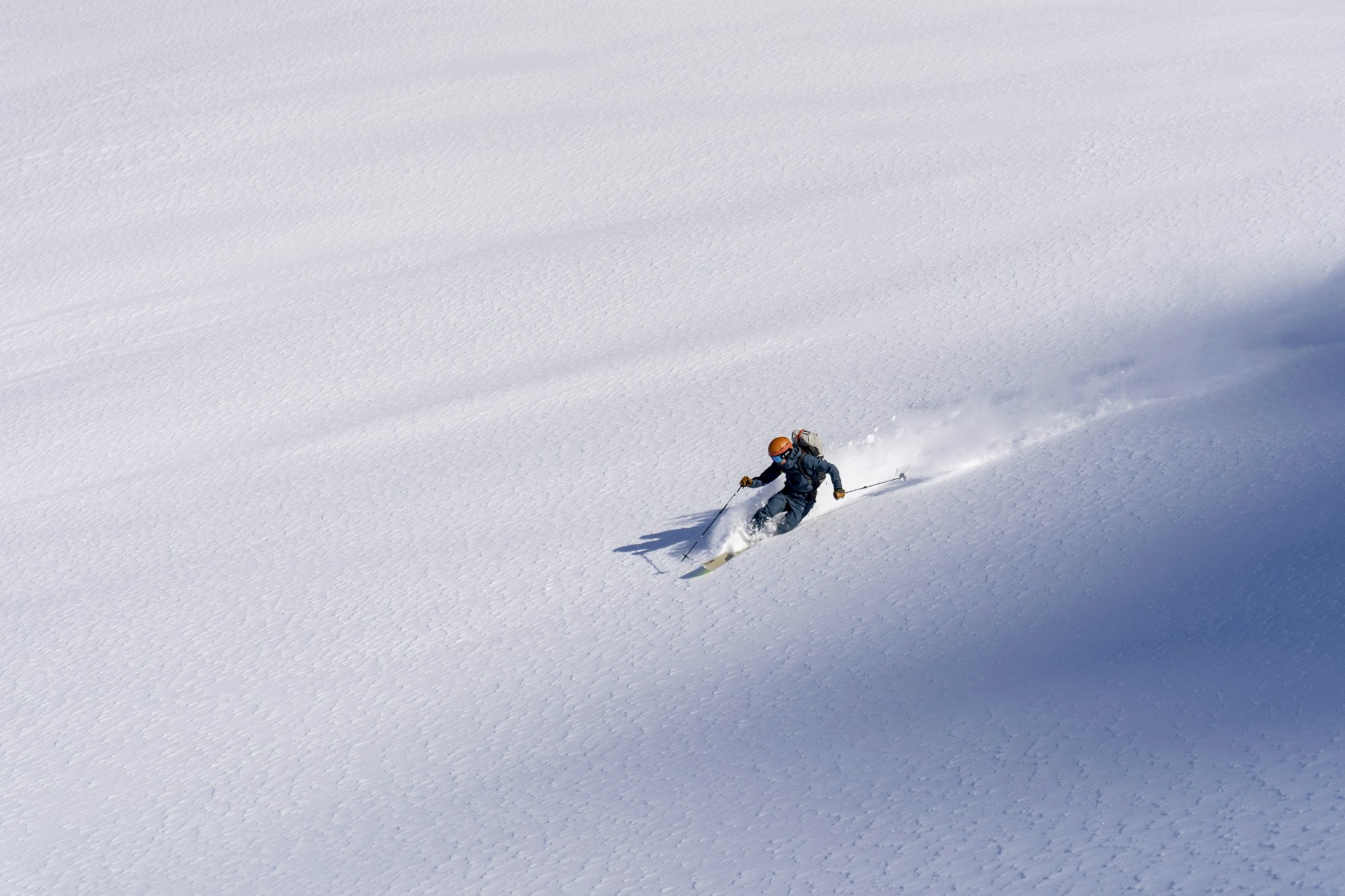 Skier carving a long turn through open powder